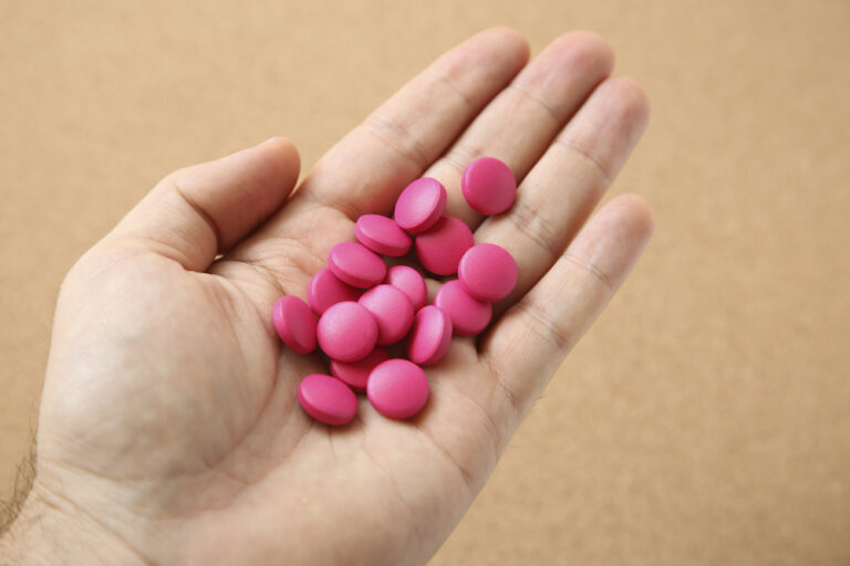 high angle shot human s hand with handful pink pills